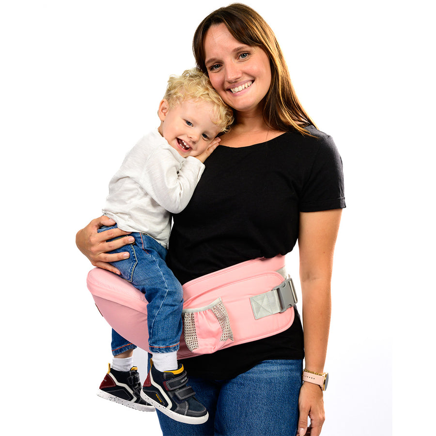 une femme souriante portant son bébé avec un porte bébé rose